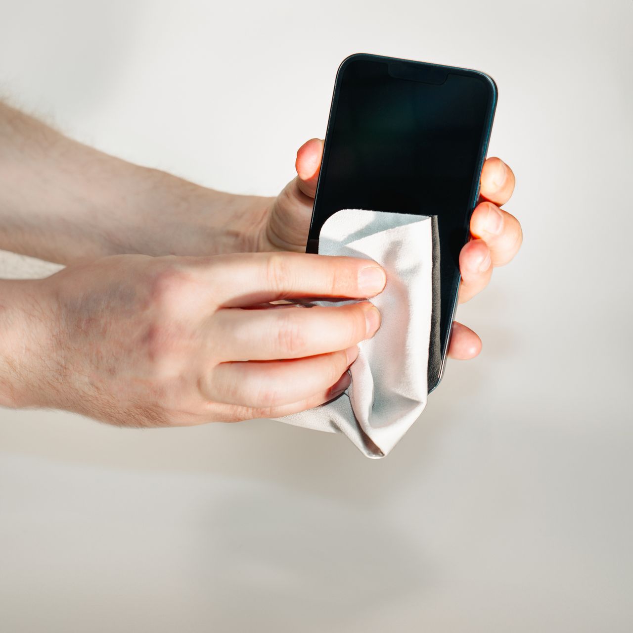 柔らかい布でスマートフォンの画面を拭いている手元