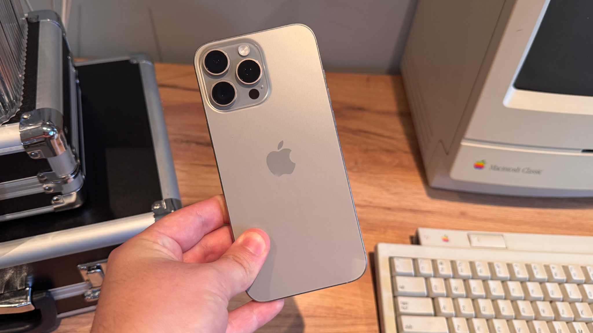 iPhone 16 Pro Maxを手に持ちトリプルカメラを見せる